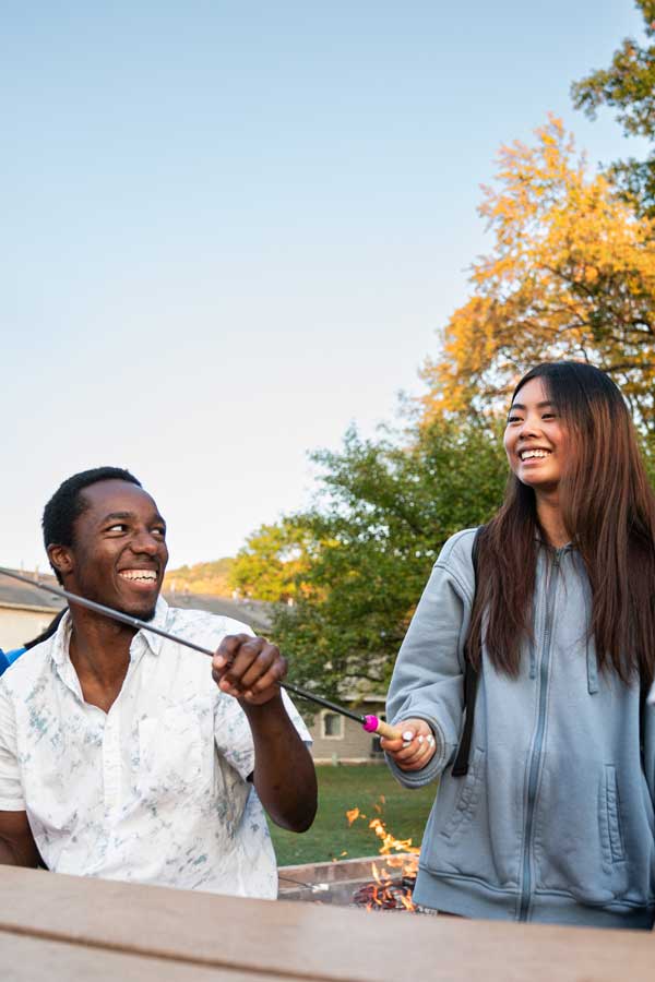 students at a bonfire talking at a picnic table