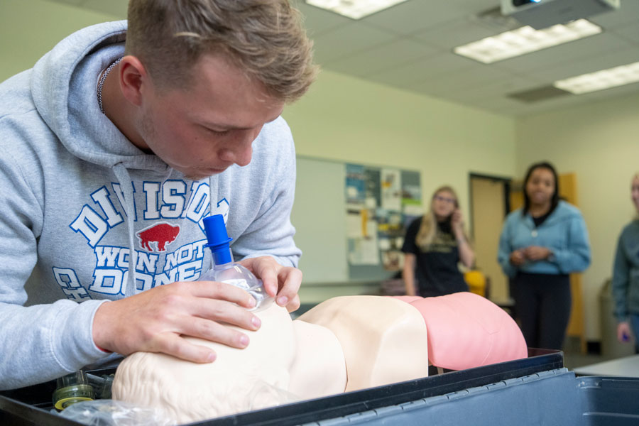 Student practicing breathing exercises on a mannequin