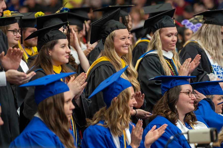 Graduates standing and clapping at commencement